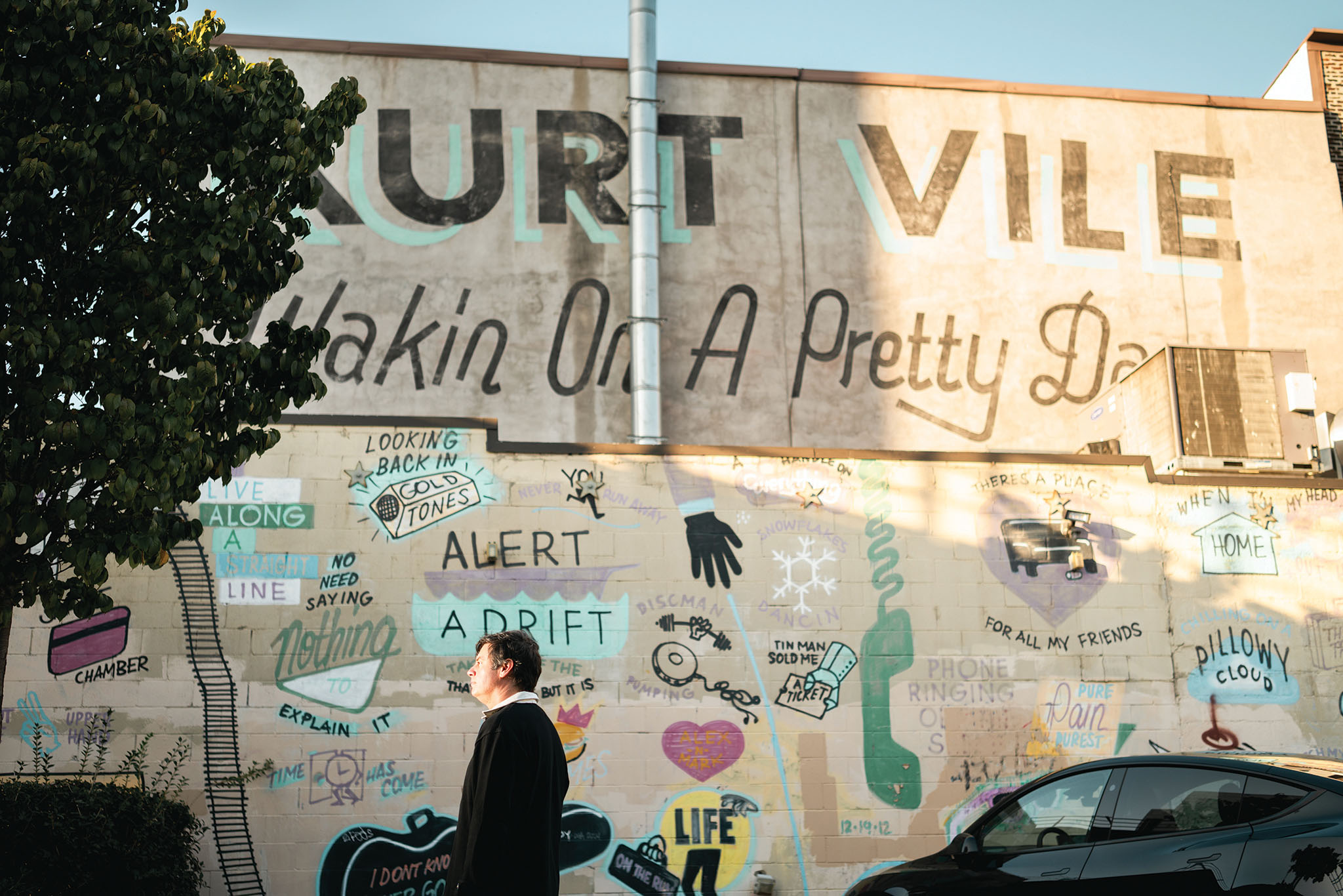 Rennie Jaffe '98 in front of a mural that says Kurt Vile Wakin' on a Pretty Daze